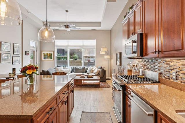 301 Clifton Ave Unit 1K, Minneapolis, MN 55403 - kitchen featuring stainless steel appliances, a ceiling fan, decorative backsplash, light stone countertops, and light wood finished floors