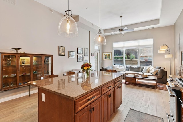 301 Clifton Ave Unit 1K, Minneapolis, MN 55403 - kitchen featuring light wood finished floors, brown cabinets, stainless steel gas stove, and light stone counters