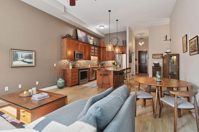 301 Clifton Ave Unit 1K, Minneapolis, MN 55403 - living room with light wood-style floors, ceiling fan, baseboards, and a towering ceiling
