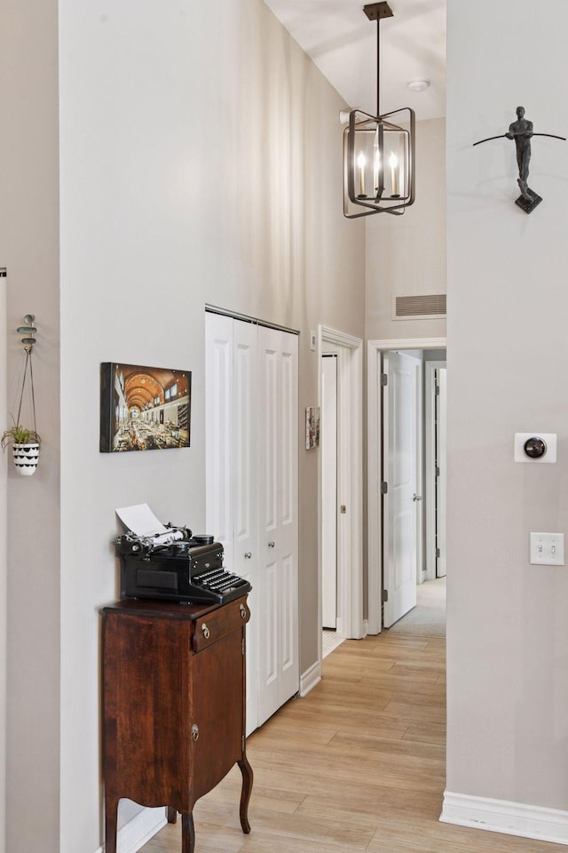 301 Clifton Ave Unit 1K, Minneapolis, MN 55403 - hall with a chandelier, light wood finished floors, a towering ceiling, and baseboards