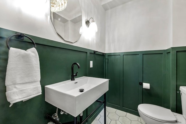 2808 32nd Ave S, Minneapolis, MN 55406 - half bath featuring a decorative wall, toilet, a sink, a wainscoted wall, and tile patterned flooring