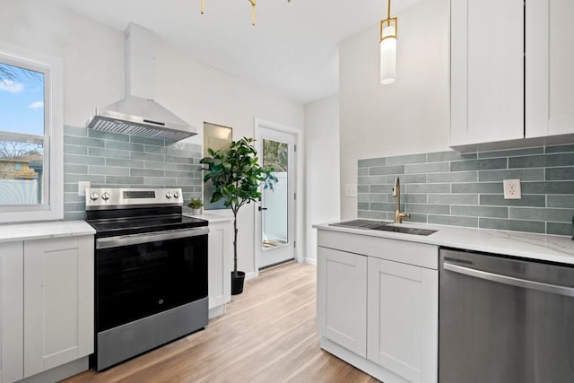 2808 32nd Ave S, Minneapolis, MN 55406 - kitchen featuring stainless steel appliances, a sink, wall chimney exhaust hood, decorative backsplash, and light wood-style floors