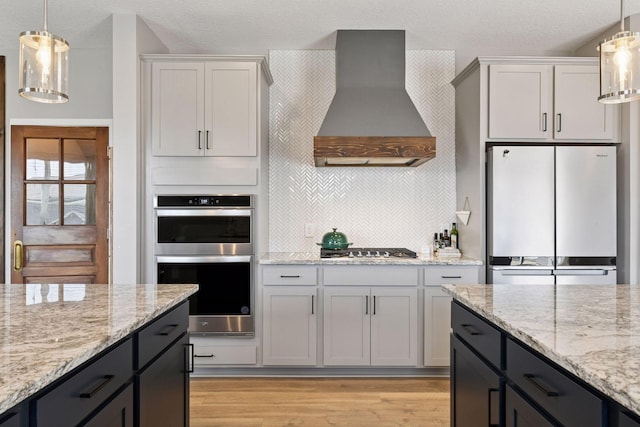515 Goldenrod Trl, Waconia, MN 55387 - kitchen with wall chimney range hood, freestanding refrigerator, double oven, light wood-style floors, and decorative light fixtures