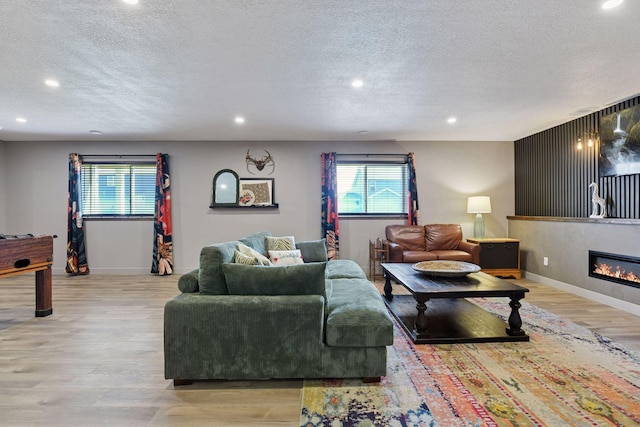 515 Goldenrod Trl, Waconia, MN 55387 - living room with a textured ceiling, recessed lighting, light wood-type flooring, baseboards, and a glass covered fireplace