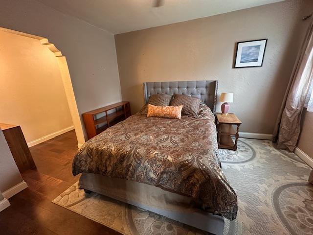 7 Shagawa Rd, Ely, MN 55731 - bedroom featuring baseboards, arched walkways, and wood finished floors