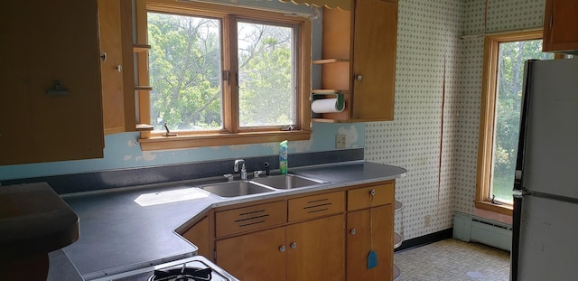 420 Spring St, River Falls, WI 54022 - kitchen featuring freestanding refrigerator, a baseboard radiator, wallpapered walls, a sink, and light countertops