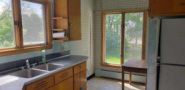420 Spring St, River Falls, WI 54022 - kitchen with freestanding refrigerator, wallpapered walls, a sink, a baseboard heating unit, and plenty of natural light