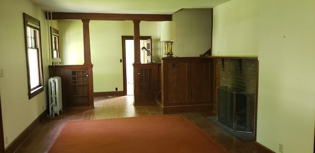 420 Spring St, River Falls, WI 54022 - hall with radiator, wood finished floors, baseboards, and decorative columns