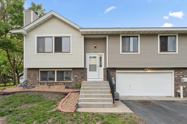 583 97th Ln NE, Blaine, MN 55434 - bi-level home with brick siding, an attached garage, a chimney, and driveway
