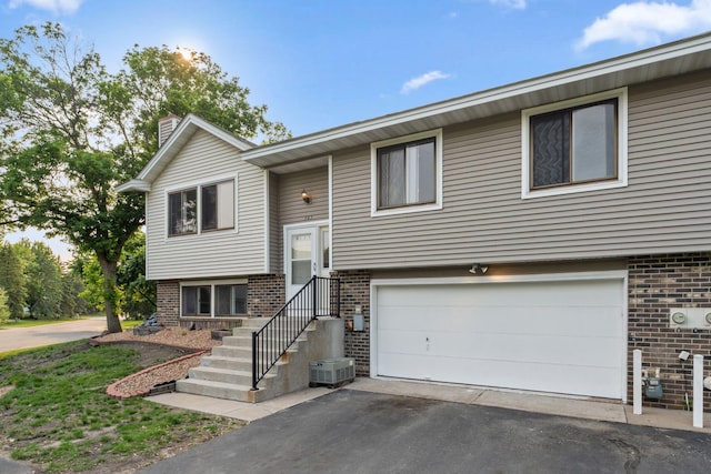 583 97th Ln NE, Blaine, MN 55434 - bi-level home featuring brick siding, a garage, a chimney, and driveway