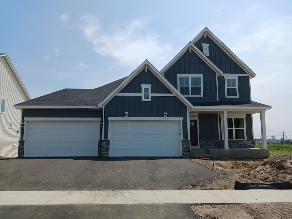 14947 106th Ave N, Maple Grove, MN 55369 - craftsman-style home featuring board and batten siding, a porch, stone siding, driveway, and a garage