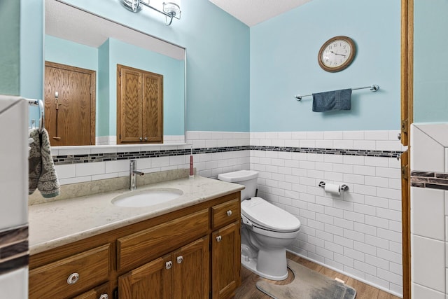 1977 Granite Ave N, Oakdale, MN 55128 - bathroom featuring toilet, wainscoting, tile walls, vanity, and wood finished floors