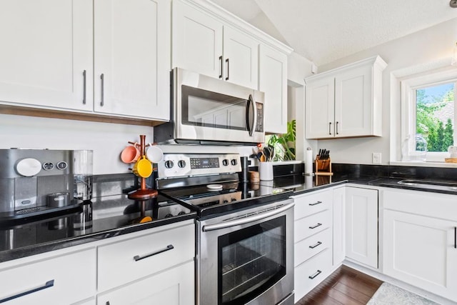 4417 Braddock Trl, Eagan, MN 55123 - kitchen featuring appliances with stainless steel finishes, white cabinets, dark countertops, lofted ceiling, and a sink
