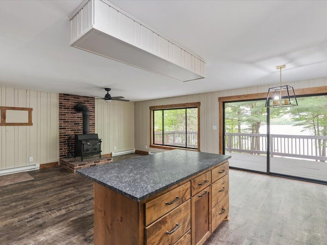 15622 Sand Beach Park, Bay Lake Twp, MN 56444 - kitchen with a baseboard heating unit, dark wood-type flooring, a wood stove, a kitchen island, and wood walls