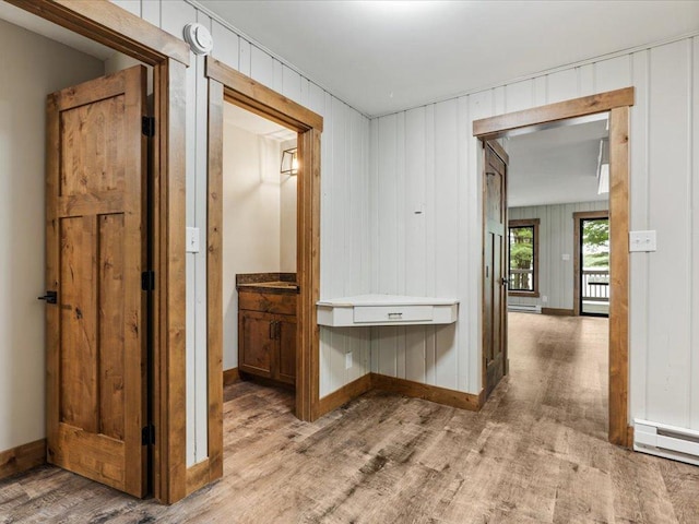 15622 Sand Beach Park, Bay Lake Twp, MN 56444 - hallway with light wood-style flooring, baseboards, a baseboard heating unit, wooden walls, and baseboard heating