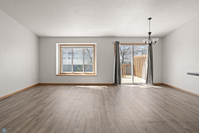 2831 Wheatland Dr S, Fargo, ND 58103 - spare room with a chandelier, wood finished floors, a textured ceiling, and baseboards