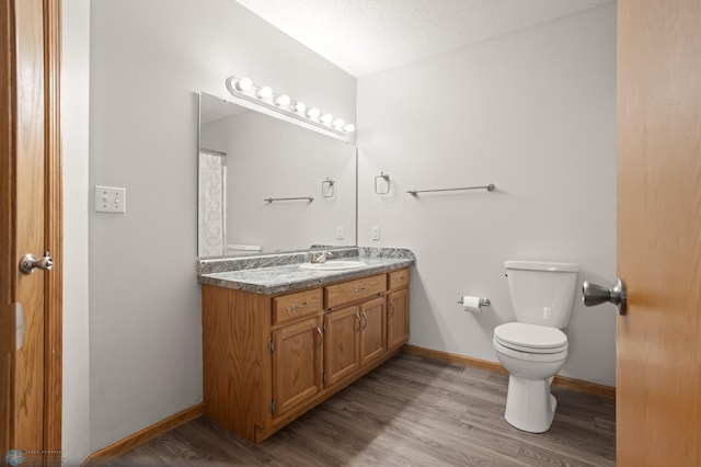 2831 Wheatland Dr S, Fargo, ND 58103 - full bathroom with toilet, vanity, wood finished floors, and baseboards