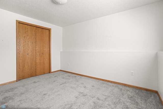 2831 Wheatland Dr S, Fargo, ND 58103 - unfurnished bedroom featuring carpet, a closet, baseboards, and a textured ceiling