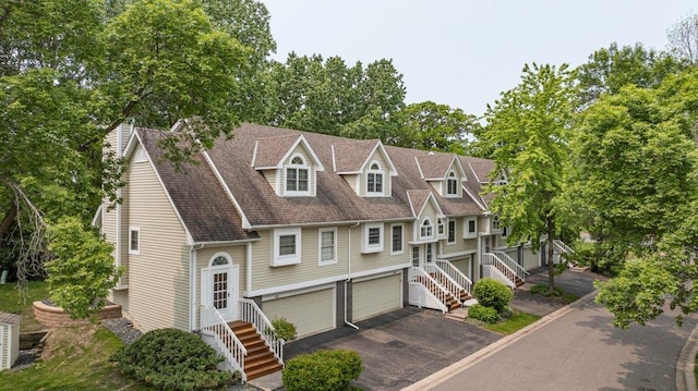 4906 Bayswater Rd, Minnetonka, MN 55345 - view of front facade with an attached garage, stairway, driveway, roof with shingles, and view of wooded area