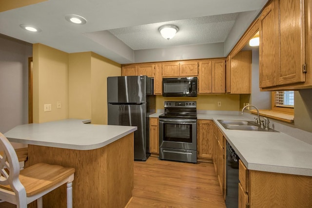 4906 Bayswater Rd, Minnetonka, MN 55345 - kitchen with black appliances, a peninsula, a sink, a kitchen bar, and light wood-style floors