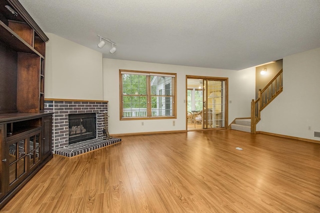 4906 Bayswater Rd, Minnetonka, MN 55345 - unfurnished living room featuring light wood finished floors, stairs, a fireplace, and a textured ceiling