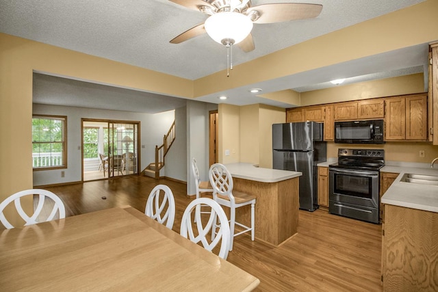 4906 Bayswater Rd, Minnetonka, MN 55345 - kitchen with appliances with stainless steel finishes, light countertops, brown cabinetry, light wood-style floors, and a ceiling fan