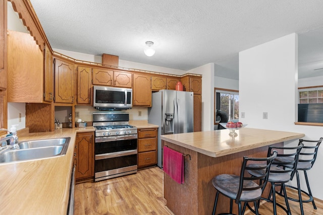 20195 Harrow Ave Way N, Forest Lake, MN 55025 - kitchen with stainless steel appliances, light wood finished floors, light countertops, a kitchen bar, and brown cabinetry