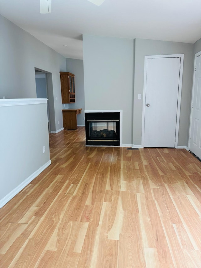 98 Magnolia Ave W, Saint Paul, MN 55117 - unfurnished living room featuring light wood-style floors, a multi sided fireplace, and baseboards