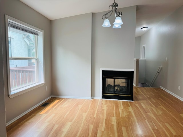 98 Magnolia Ave W, Saint Paul, MN 55117 - unfurnished living room with wood finished floors, baseboards, a chandelier, and a multi sided fireplace