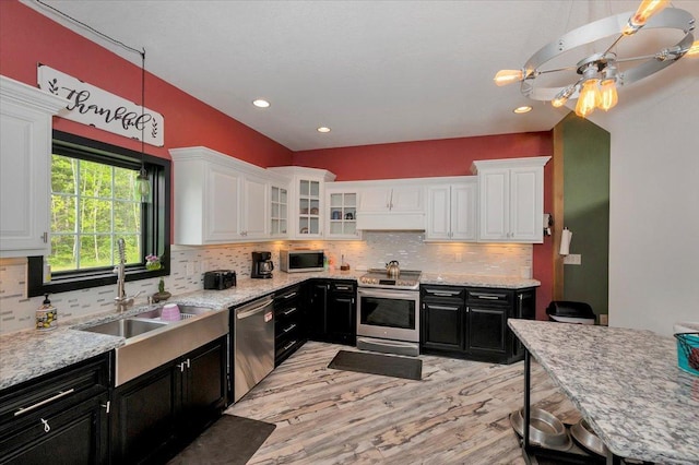 4985 Sam Anderson Rd, Amnicon Twp, WI 54874 - kitchen featuring appliances with stainless steel finishes, dark cabinets, white cabinetry, light wood-style floors, and a sink