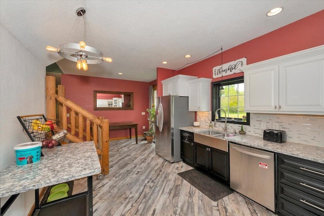 4985 Sam Anderson Rd, Amnicon Twp, WI 54874 - kitchen with appliances with stainless steel finishes, a sink, white cabinets, light wood-style flooring, and decorative backsplash