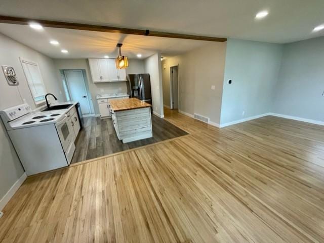 4155 7th St, Goodview, MN 55987 - kitchen with electric range, fridge with ice dispenser, white cabinets, wood finished floors, and a sink