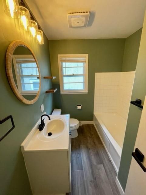 4155 7th St, Goodview, MN 55987 - full bath with toilet, vanity, a bath, wood finished floors, and baseboards