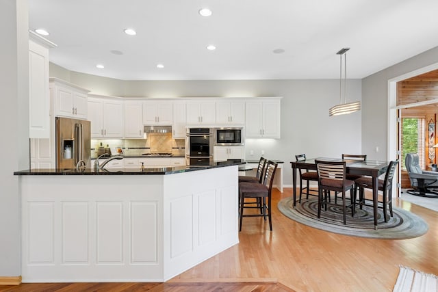 6654 Orchid Ln N, Maple Grove, MN 55311 - kitchen featuring stainless steel appliances, a peninsula, under cabinet range hood, light wood-style flooring, and backsplash