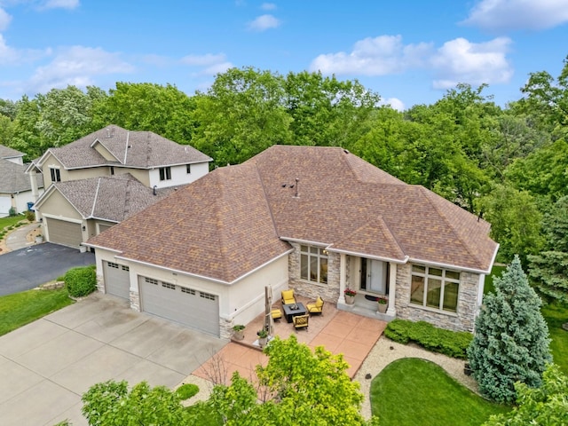 6654 Orchid Ln N, Maple Grove, MN 55311 - back of house featuring stone siding, driveway, a garage, and roof with shingles