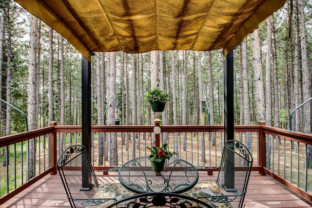 20929 Faron Dr, Nevis, MN 56467 - wooden terrace featuring outdoor dining space and a wooded view