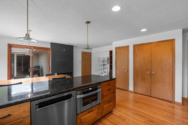 11411 Johnson Cir, Bloomington, MN 55437 - kitchen with stainless steel appliances, a textured ceiling, brown cabinetry, light wood-type flooring, and hanging light fixtures