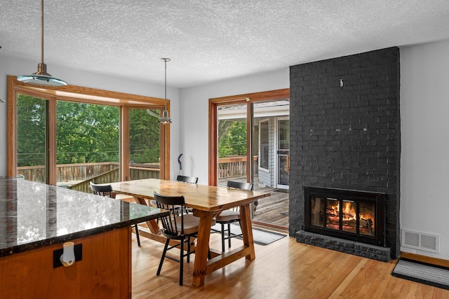 11411 Johnson Cir, Bloomington, MN 55437 - dining space featuring a textured ceiling, light wood-style floors, and a fireplace