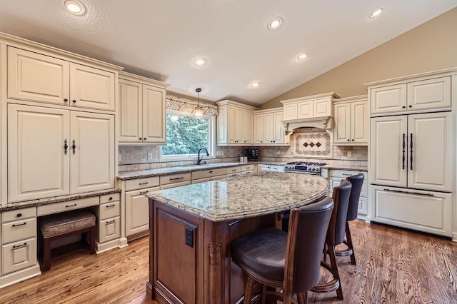 9025 Mcguffey Rd, Eden Prairie, MN 55347 - kitchen featuring paneled fridge, a breakfast bar, a kitchen island, vaulted ceiling, and light wood-style flooring