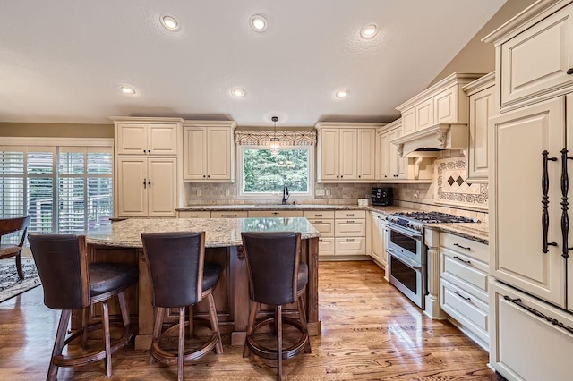 9025 Mcguffey Rd, Eden Prairie, MN 55347 - kitchen featuring double oven range, paneled fridge, a breakfast bar, light stone countertops, and a center island
