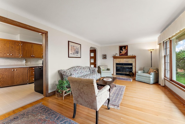 2142 Cottage Ave E, Saint Paul, MN 55119 - living area with a tiled fireplace, light wood-style flooring, arched walkways, and baseboards