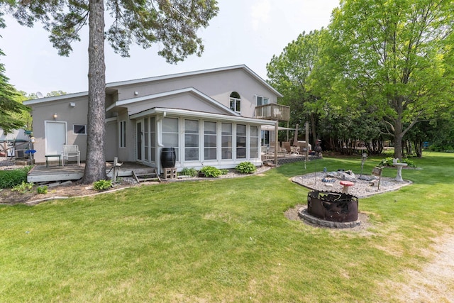 17159 Stalker Lake Rd, Battle Lake, MN 56515 - rear view of property with a deck, a sunroom, a lawn, a fire pit, and stucco siding