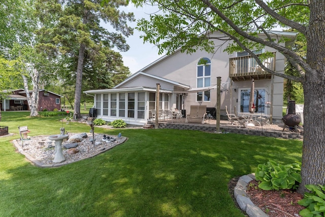 17159 Stalker Lake Rd, Battle Lake, MN 56515 - rear view of house with a balcony, a patio, a lawn, a sunroom, and stucco siding
