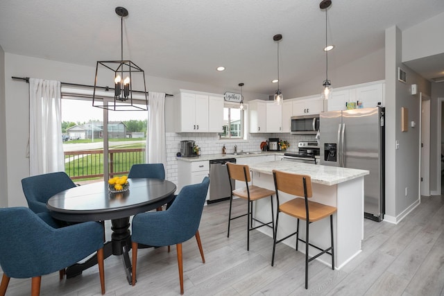 3900 Orchardview Ln NW, Rochester, MN 55901 - kitchen with appliances with stainless steel finishes, decorative backsplash, white cabinetry, a kitchen island, and a chandelier
