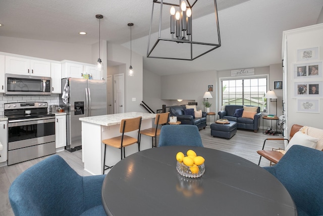 3900 Orchardview Ln NW, Rochester, MN 55901 - dining area with light wood-style flooring, vaulted ceiling, a chandelier, and a textured ceiling