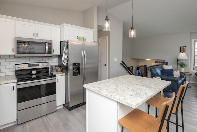 3900 Orchardview Ln NW, Rochester, MN 55901 - kitchen featuring appliances with stainless steel finishes, vaulted ceiling, light wood-style flooring, white cabinetry, and tasteful backsplash