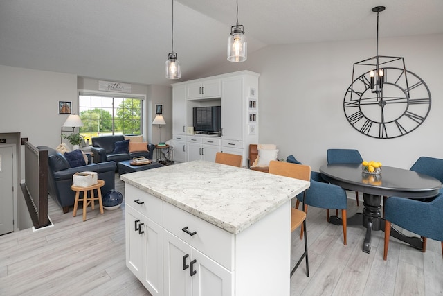 3900 Orchardview Ln NW, Rochester, MN 55901 - kitchen featuring light wood finished floors, a kitchen island, lofted ceiling, decorative light fixtures, and white cabinets
