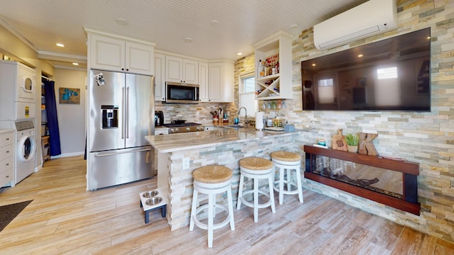 27096 Little Floyd Lake Rd Unit 2, Detroit Twp, MN 56501 - kitchen with stainless steel appliances, a wall unit AC, stacked washer / dryer, light wood finished floors, and a sink