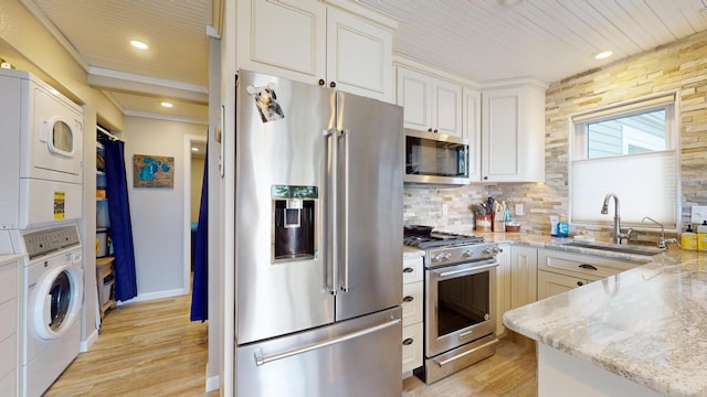 27096 Little Floyd Lake Rd Unit 2, Detroit Twp, MN 56501 - kitchen with high quality appliances, estacked washer and dryer, a sink, light wood-type flooring, and tasteful backsplash