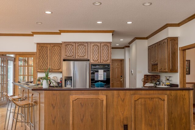 17 Oriole Pl, North Mankato, MN 56003 - kitchen featuring stainless steel fridge, dark countertops, crown molding, a textured ceiling, and a peninsula